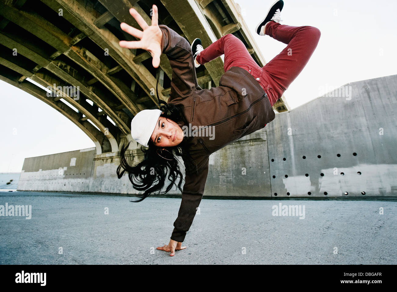Le break dance femme hispanique sous viaduc Banque D'Images