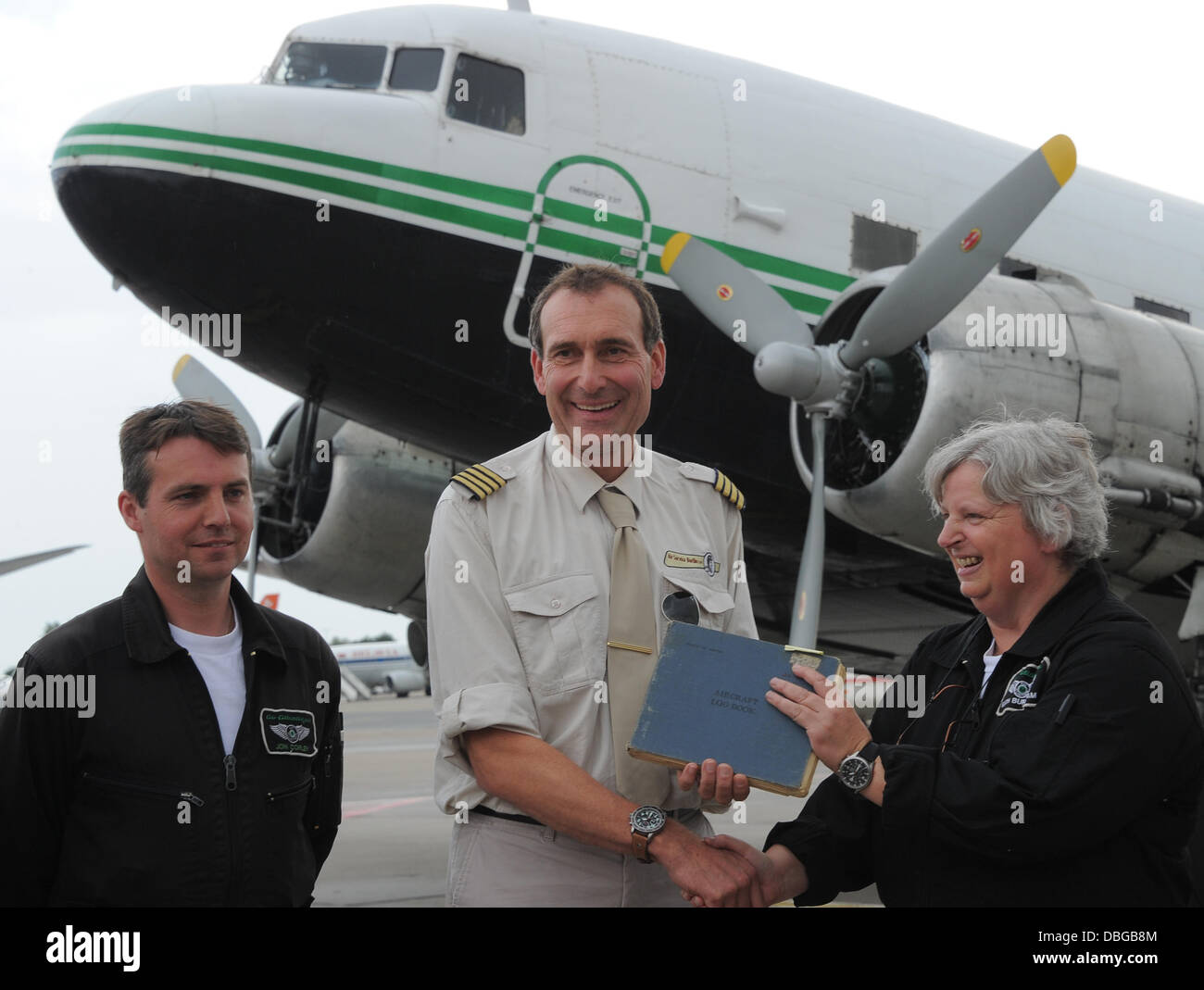 L'équipage anglais avec John Corley (L) et Kath Burnham (R) se tenir en face d'un DC-3 Bombardier Raisin à l'aéroport avec Frank Ollivier (C, Air Service Berlin Schoenefeld), Allemagne, 30 juillet 2013. Il a été livré à l'US Air Force comme C-47B 43-49474 en 1944. En 1949, l'aéronef a été utilisé dans le blocus de Berlin. L'association des bombardiers raisin acheté l'avion à Coventry et veut l'utiliser pour les pièces pour reconstruire le Raisin Berlin Bombardier. Photo : BERND SETTNIK Banque D'Images