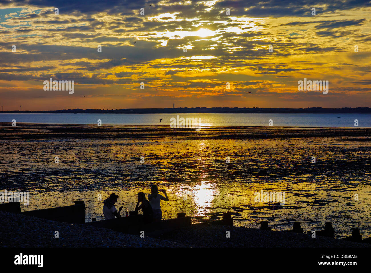 Les gens de prendre un verre au coucher du soleil sur la plage à Whitstable Kent Banque D'Images