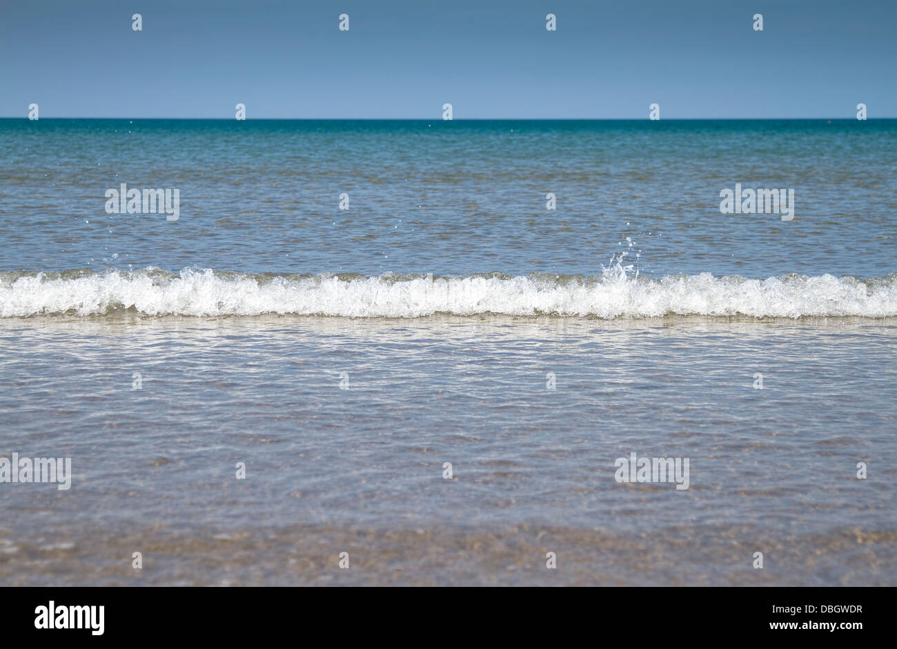 Plage avec ciel bleu et de petites vagues se brisant à Barmouth, Wales UK Banque D'Images