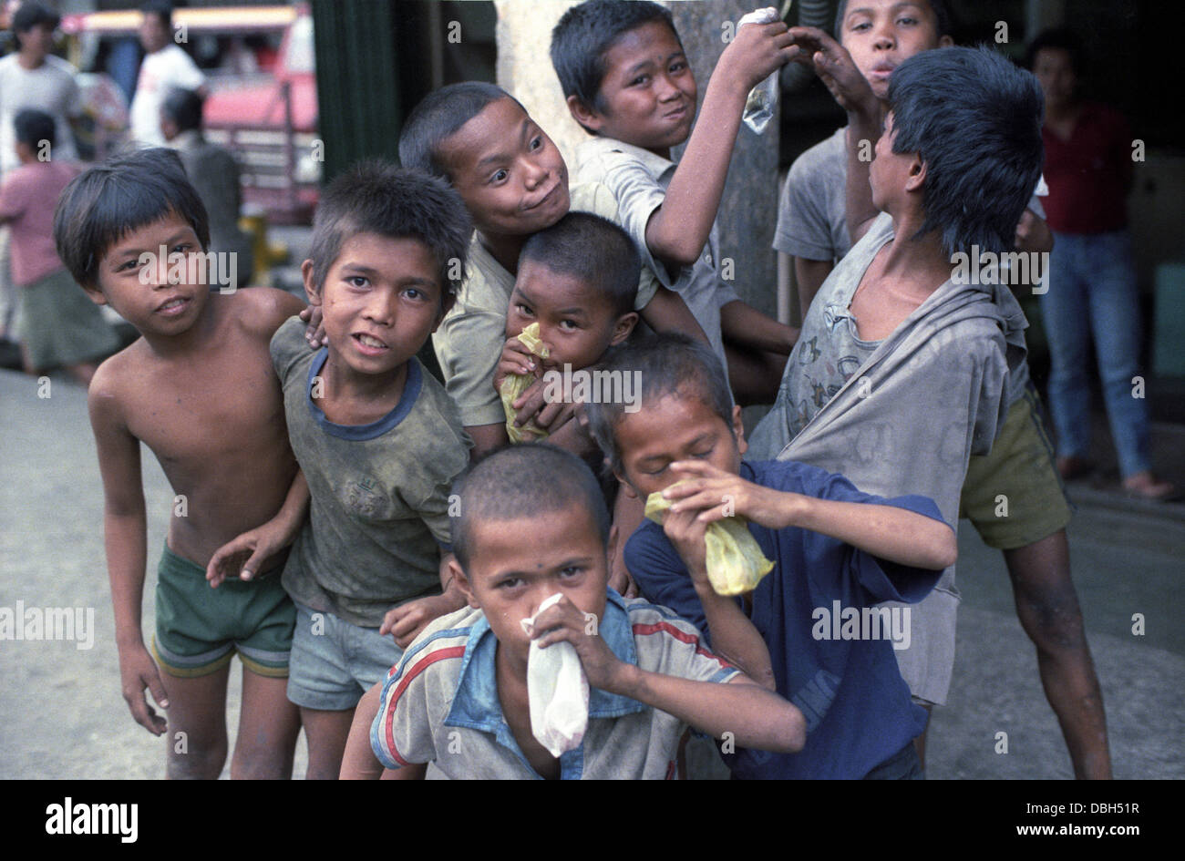 1984 Manille, Philippines, les garçons de la rue appelé il y a des passagers clandestins, clown et renifler leur colle. Banque D'Images