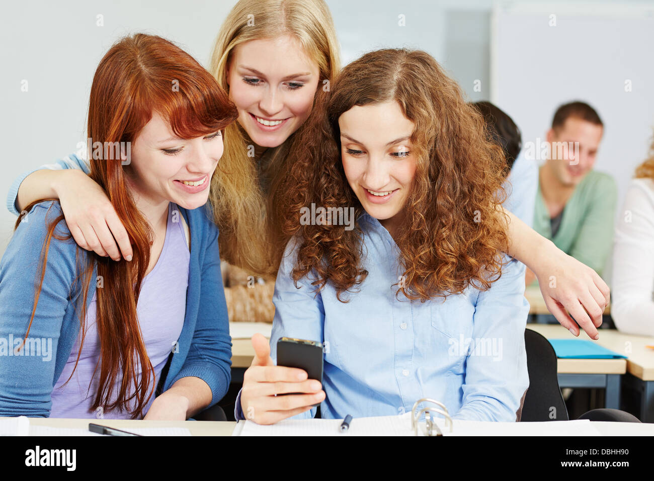 Trois femmes heureux contrôler les médias sociaux avec un smartphone à l'université Banque D'Images