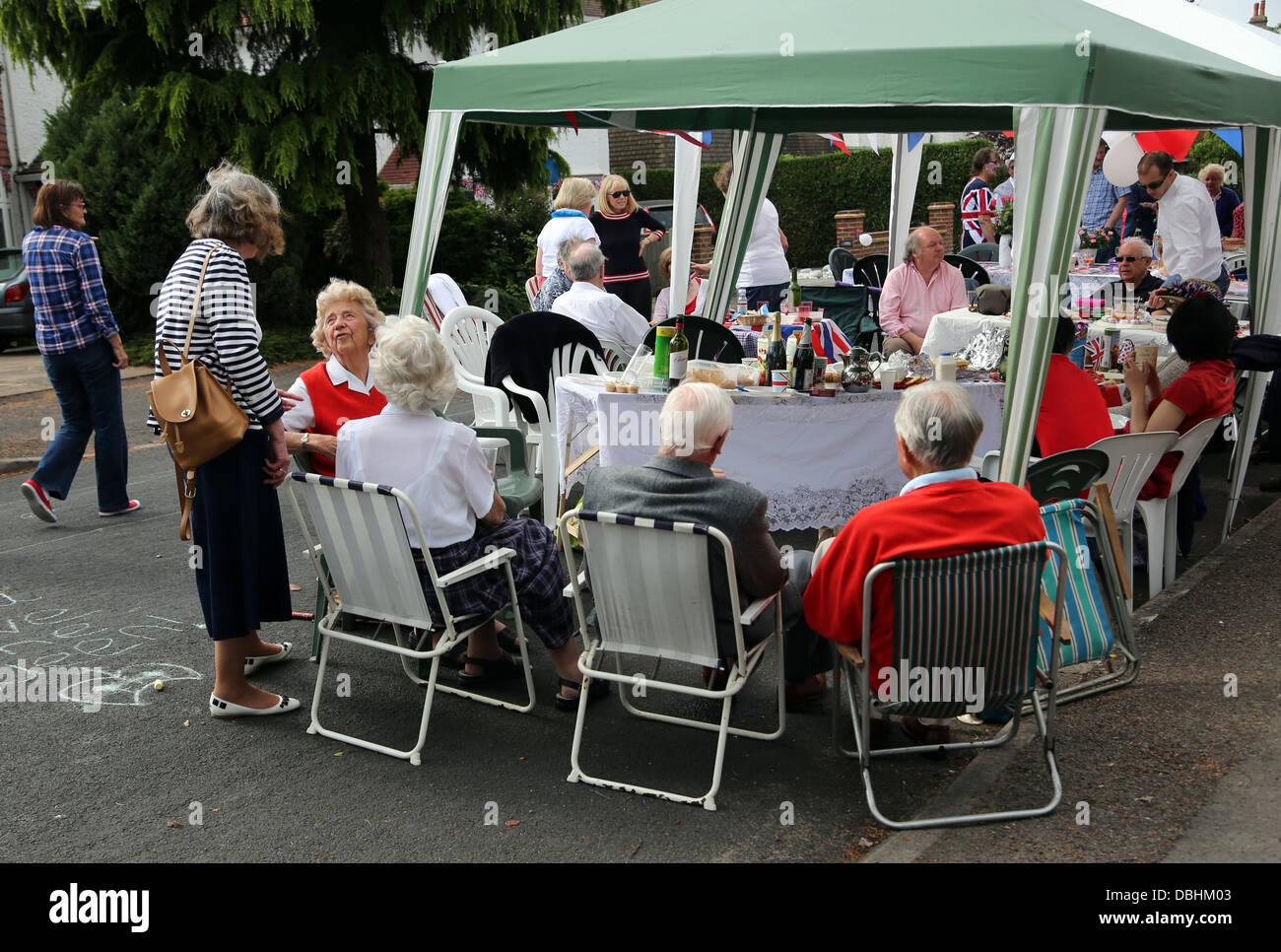 Les gens assis à l'ombre des parasols et chapiteaux de manger et boire à la fête dans la rue pour le Jubilé de diamant de la Reine Angleterre Surrey Banque D'Images