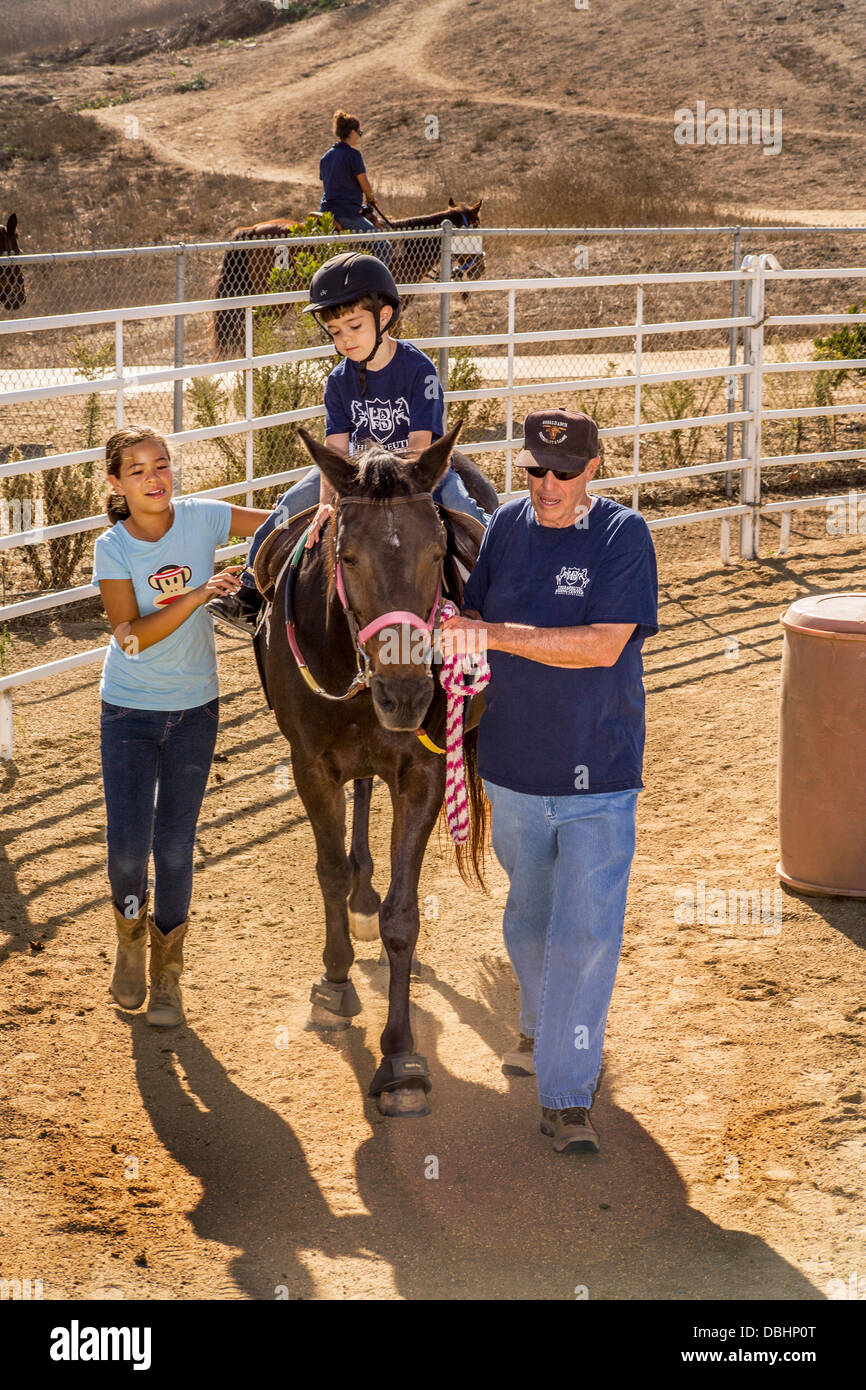 Un garçon atteint de la maladie de Willebrand Van et l'autisme de haut niveau ridea un cheval dans le cadre de l'équitation thérapeutique Banque D'Images