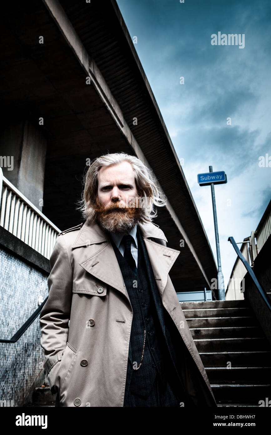 Homme barbu en costume et manteau walking down steps dans un métro. Banque D'Images