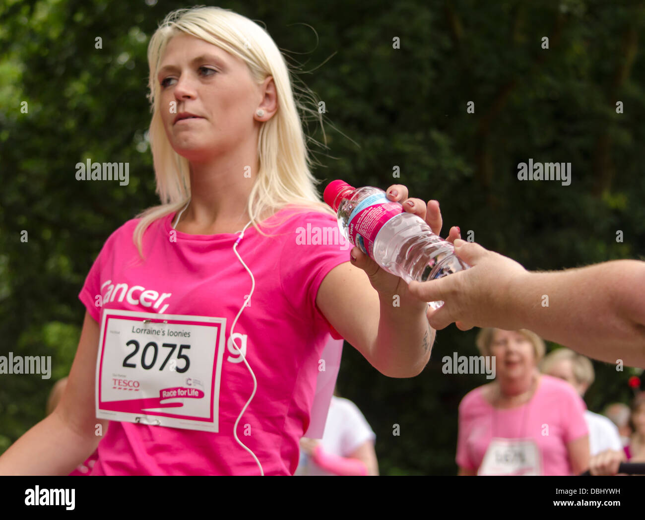 Femme tenant une bouteille d'eau sur une course pour la vie UK Banque D'Images