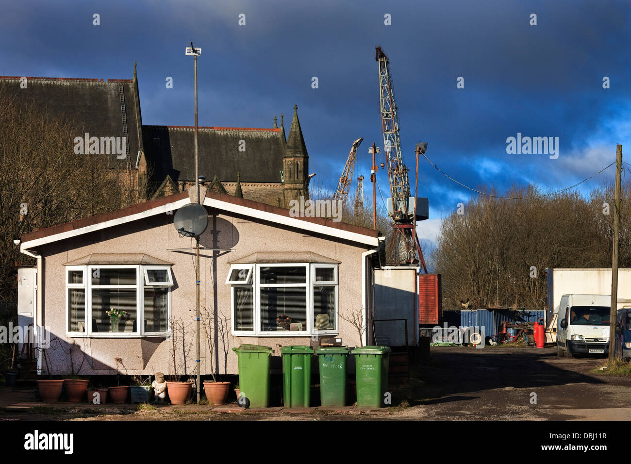 Petite maison sur le terrain de Govan Shipbuilding avec une grue à flèche relevable à l'arrière-plan, Glasgow, Écosse, Royaume-Uni Banque D'Images