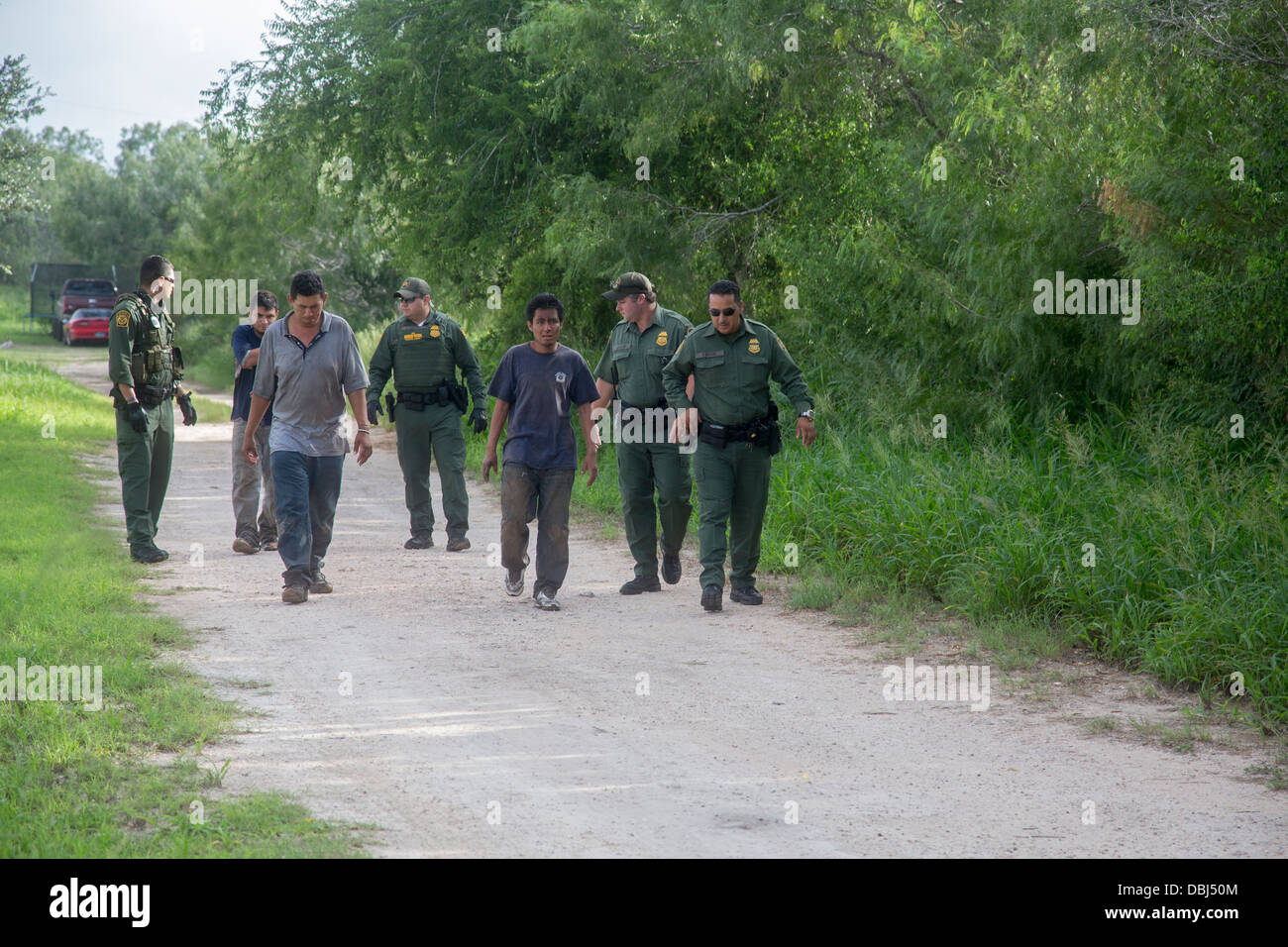 Agents de patrouille frontalière escort trois immigrants sans papiers d'Amérique centrale après un van holding 26 s'est écrasé sur une route du Texas Banque D'Images