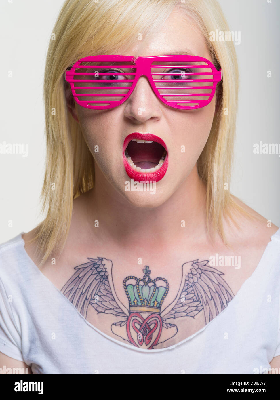 Les jeunes libre avec un grand tatouage de Claddagh sur la poitrine portant des lunettes à fentes rose Banque D'Images