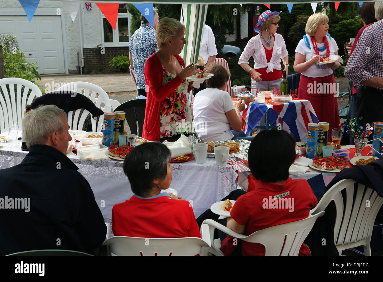 Les gens assis à l'ombre des parasols et chapiteaux de manger et boire à la fête dans la rue pour le Jubilé de diamant de la Reine Angleterre Surrey Banque D'Images