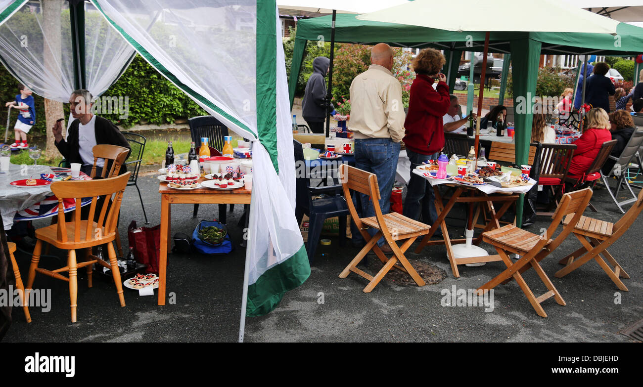 Les gens assis à l'ombre des parasols et chapiteaux de manger et boire à la fête dans la rue pour le Jubilé de diamant de la Reine Angleterre Surrey Banque D'Images