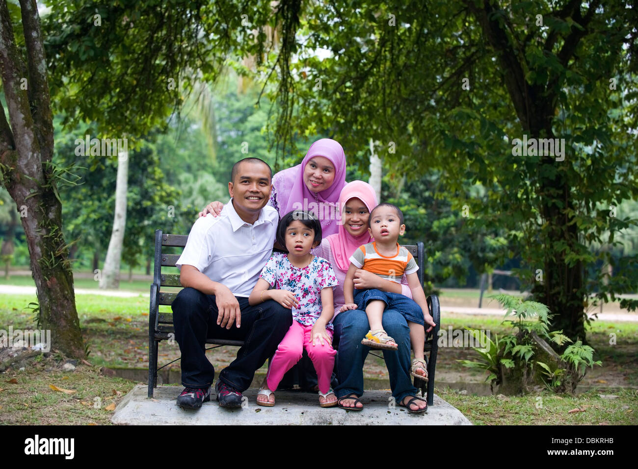 Famille malais assis et s'amuser dans le parc Banque D'Images