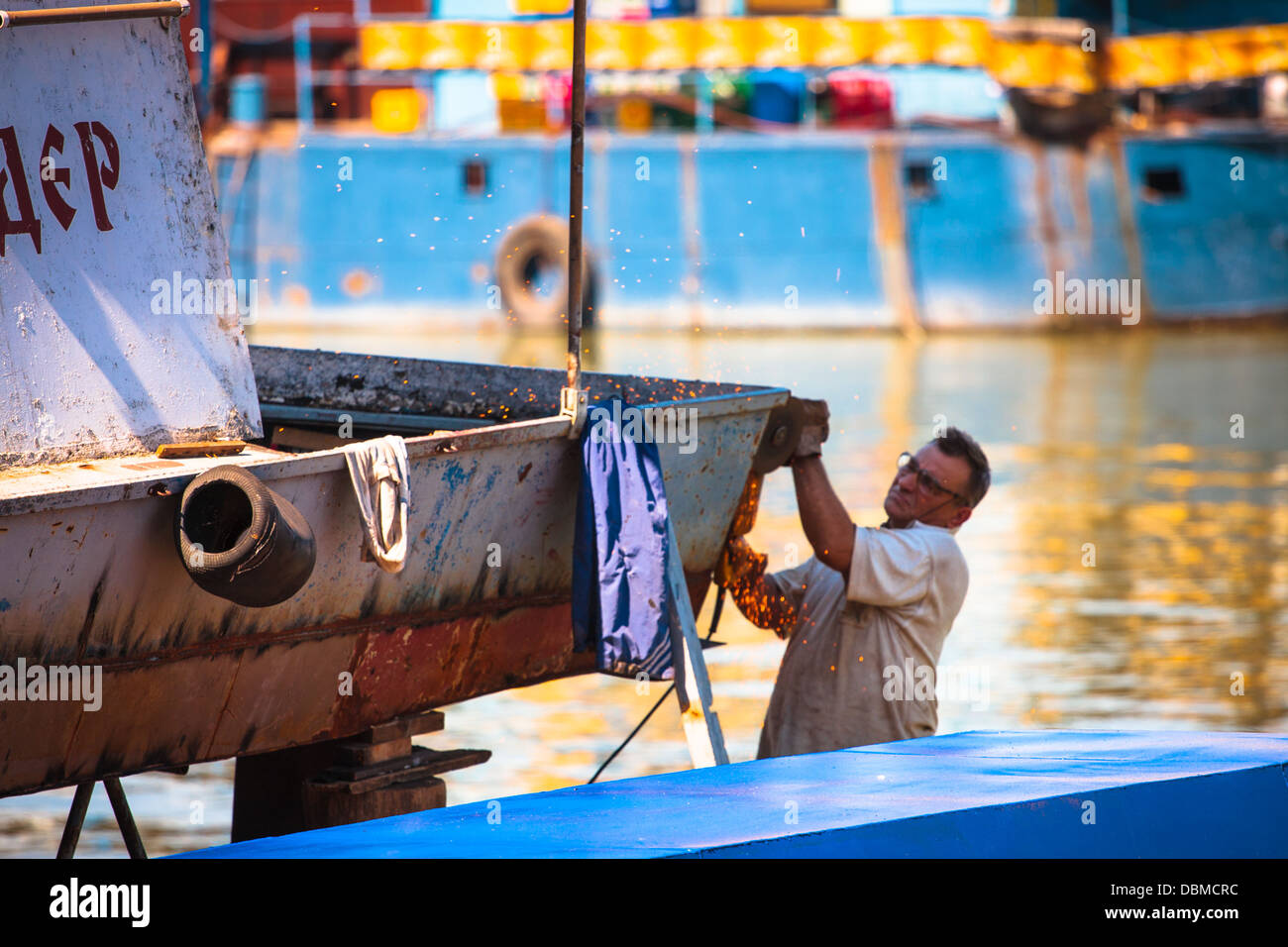 Un homme tente de réparer et nettoyer son bateau sur le Danube à Belgrade, Serbie Banque D'Images