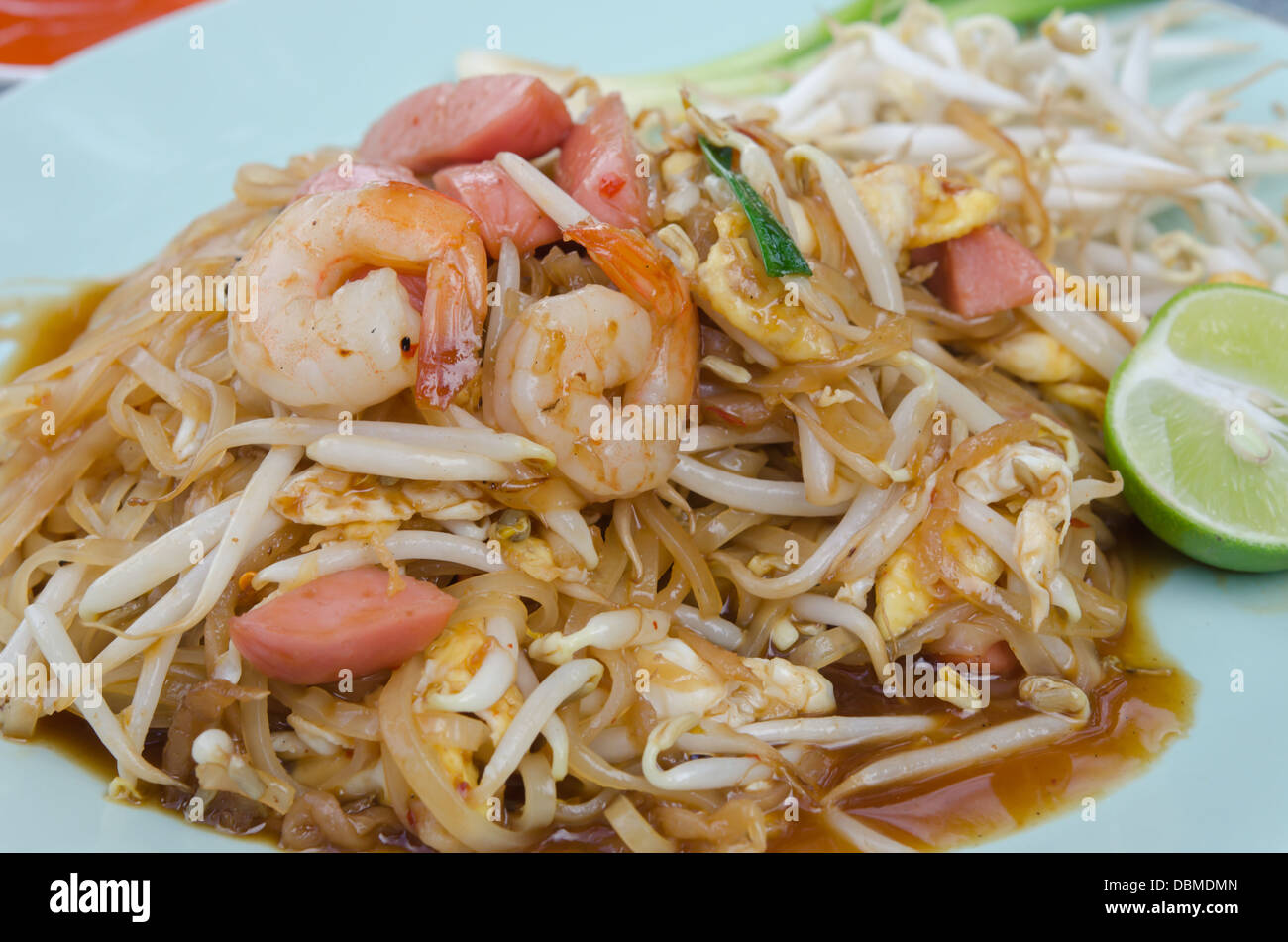 Close up avec des nouilles sautées, crevettes saucisse , l'oeuf et de légumes frais servis avec lime slice Banque D'Images