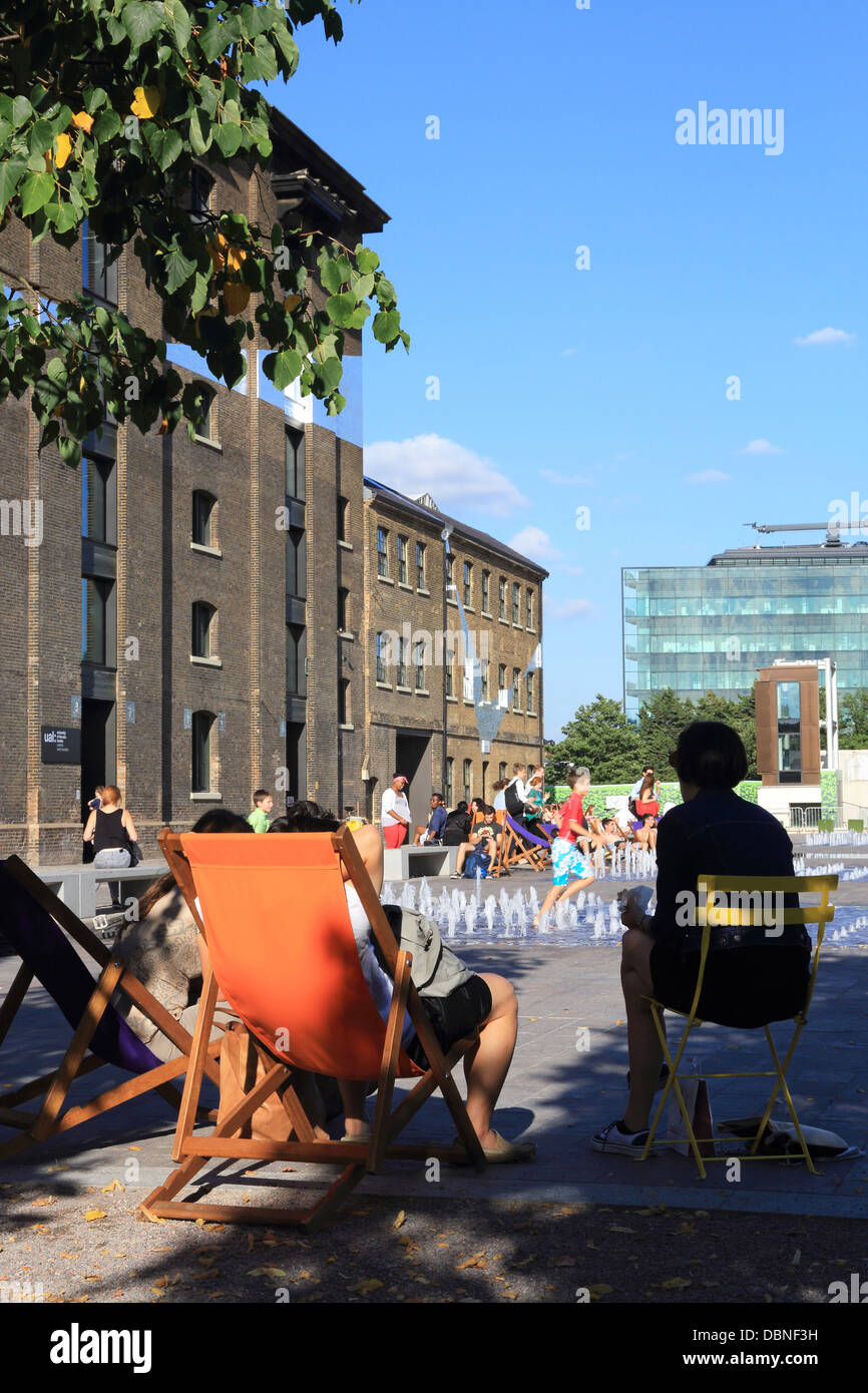 Les gens se détendre sur une chaude soirée d'été, sur la place du grenier, NC1, dans la zone de régénération de Kings Cross, au nord de Londres. Banque D'Images
