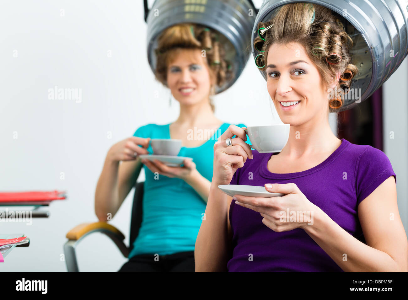 La femme à la coiffure de boire du café ou du cappuccino et chit-chat, tandis que vos cheveux séchage sous un sèche-cheveux Banque D'Images