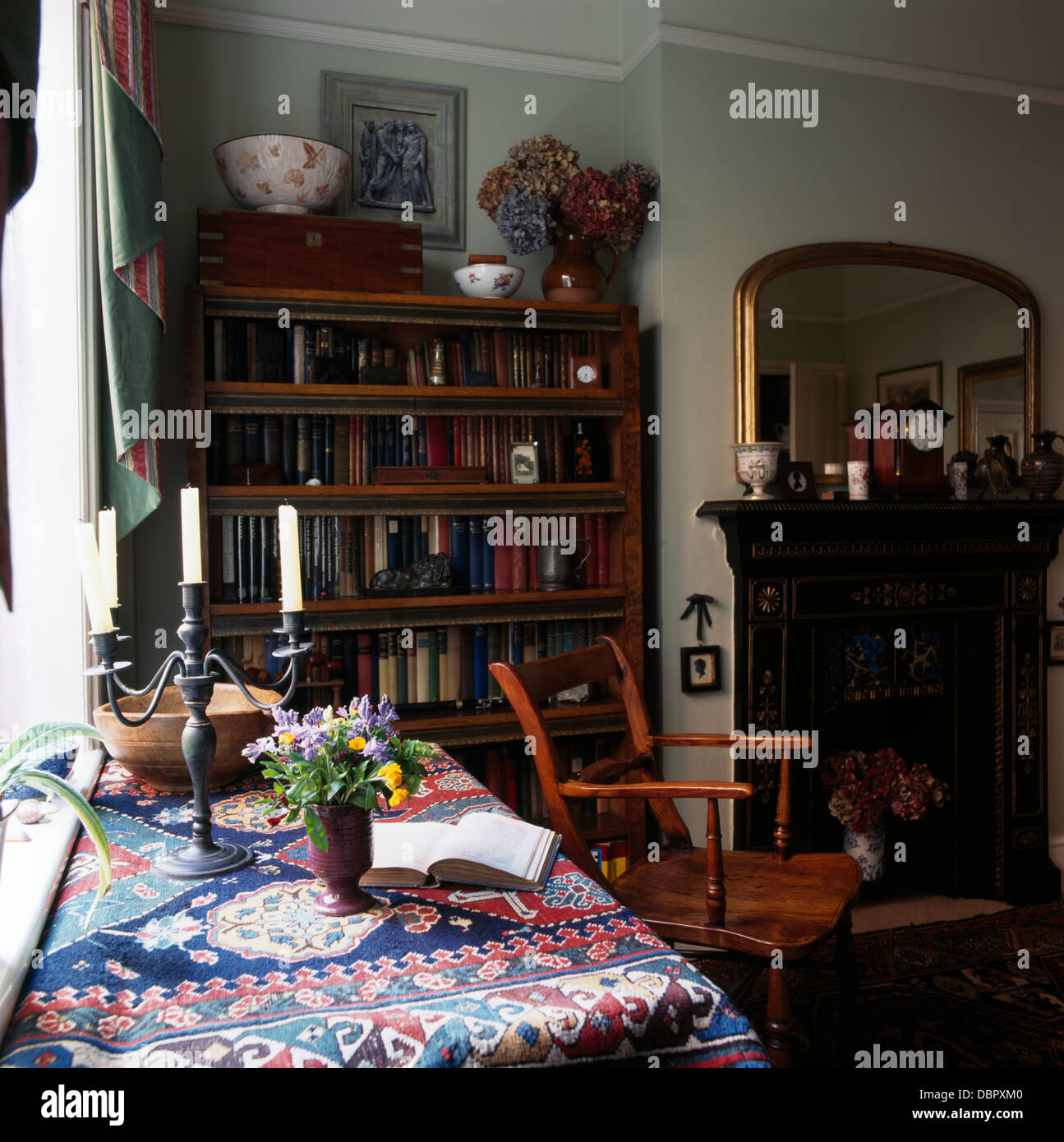 Chandelier en étain sur table avec un chiffon à motifs dans la salle à manger avec bibliothèque dans une alcôve à côté cheminée Banque D'Images
