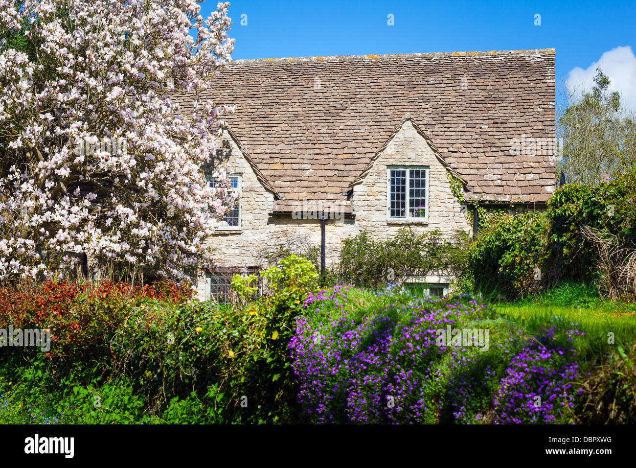 Maison en pierre entourée de fleurs dans un village anglais rural Banque D'Images