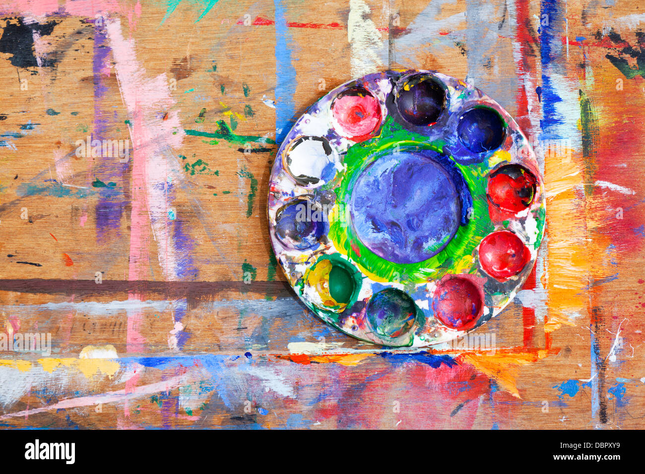 Close-up of a multi-couleur de peinture en plastique sur une planche de bois éclaboussé de peinture. Banque D'Images