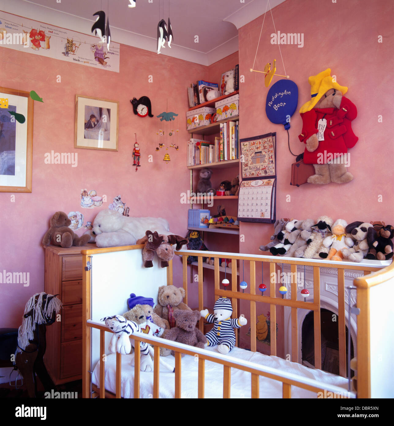 Les jouets mous dans lit bébé en rose nursery chambre avec grand ours  Paddington avis sur le mur Photo Stock - Alamy