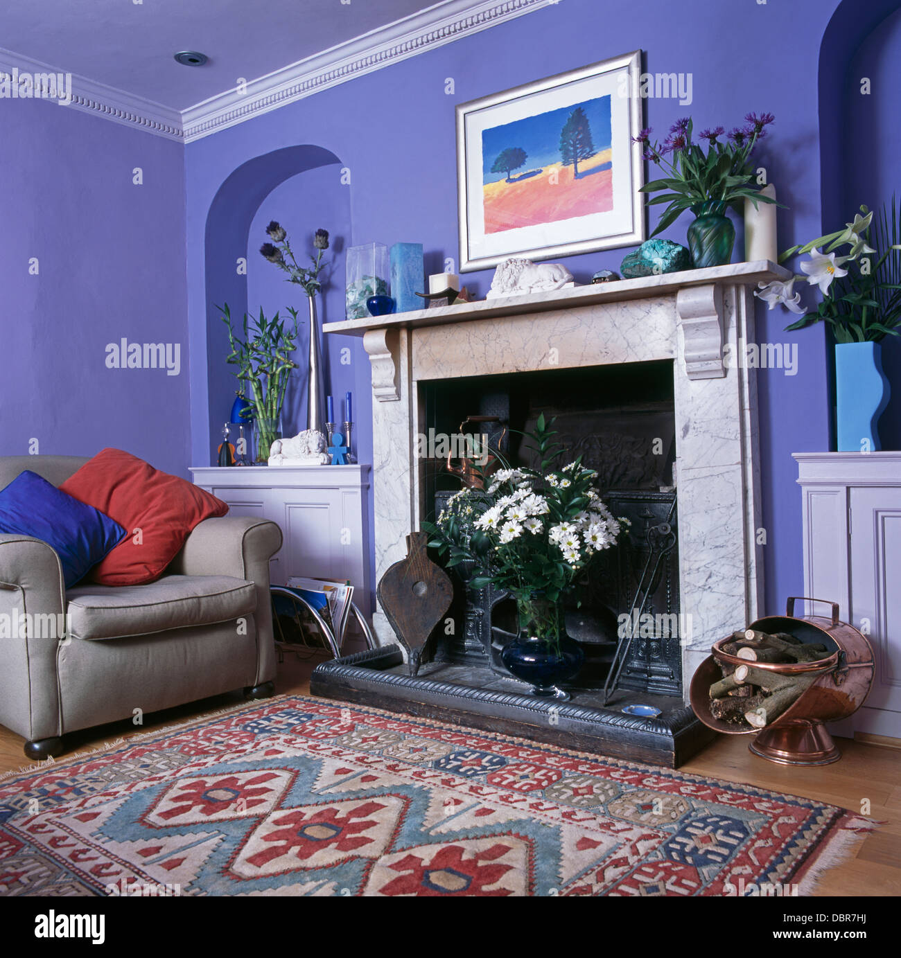 Tapis à motifs en face de la cheminée de marbre en bleu salon avec fauteuil gris avec des coussins rouge et bleu en face de l'alcôve Banque D'Images