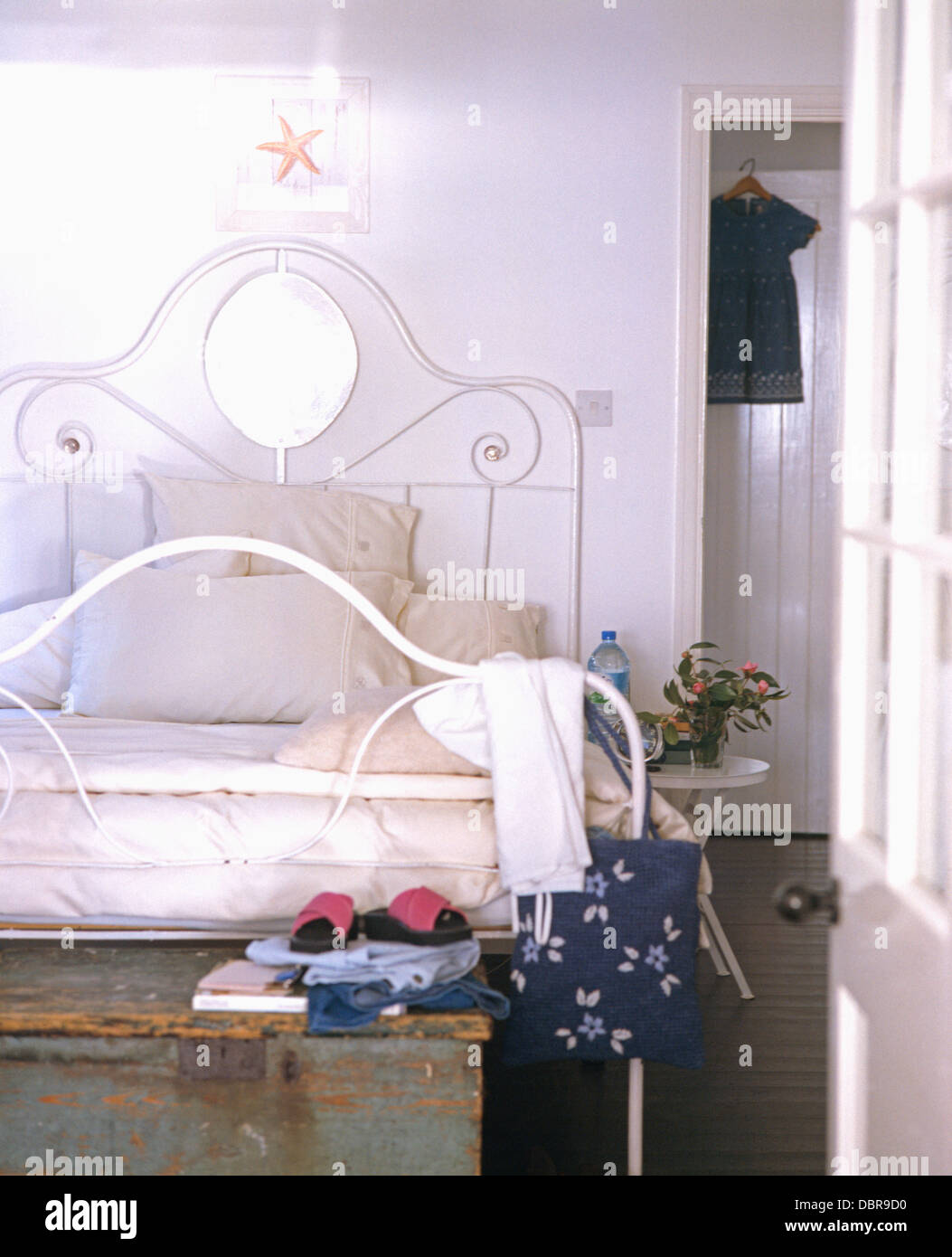 Porte ouverte à la petite maison chambre avec lit en fer forgé blanc empilé  avec oreillers et vieux coffre en bois au pied du lit Photo Stock - Alamy