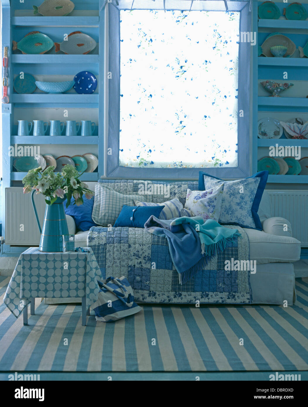 Tapis bleu +blanc à rayures sur le sol en face de canapé bleu avec mosaïque  de cottage salon avec étagères bleu pâle Photo Stock - Alamy