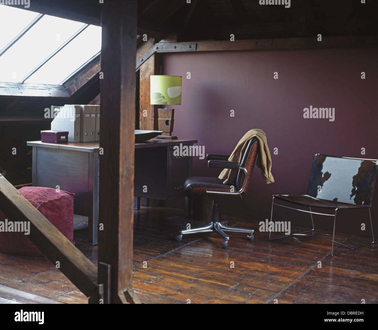 La peau de poney coussin sur une chaise en cuir violet foncé dans l'étude de conversion loft avec fauteuil pivotant à 24 et de parquet et de poutres Banque D'Images