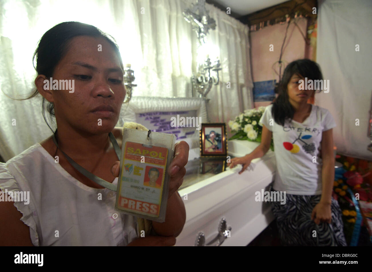 La ville de General Santos, Philippines du Sud. 3 Août, 2013. L'épouse de Mario Sy Violeta Sy (L) presse ID de mari Mario Sy comme ils pleurent après le corps de Mario Sy seulement arrivent dans leur chambre à midi à Santa Cruz Silway, General Santos City, Philippines du Sud, 03 août 2013. Offres news photographe Mario Sy a été tourné à l'intérieur de son domicile Vendredi, 01 août 2013. Sy a contribué à "photos de presse à l'APOL News Bulletin(Sur cible News Bulletin). Jubelag Sapol Editeur Jonh Paul a déclaré que la question des drogues illégales dans la zone Sy pourrait être le motif. Banque D'Images