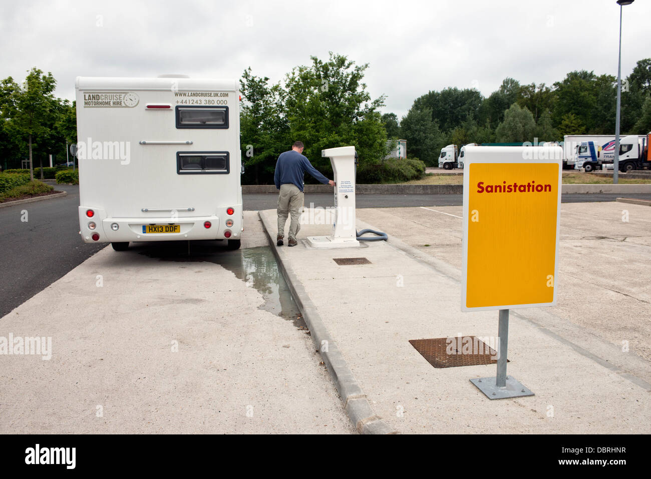Un camping-car avec un camping à l'aide d'un flot Bleu 'Français' à un point de service aire sur une autoroute en France Banque D'Images