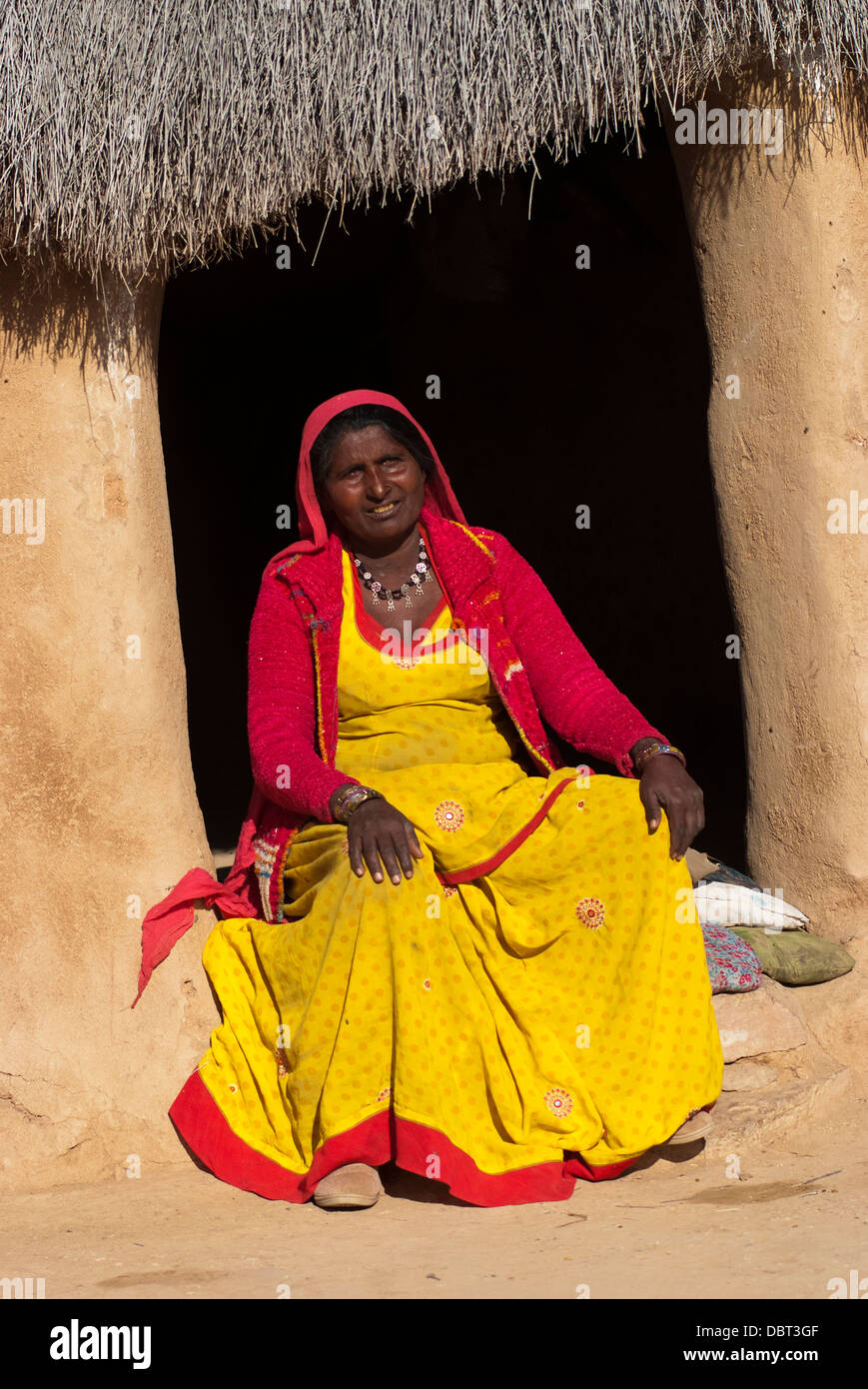 Une femme en sari jaune vif assis devant sa hutte de terre le 27 février 2013 à Jaisalmer, Inde. Banque D'Images