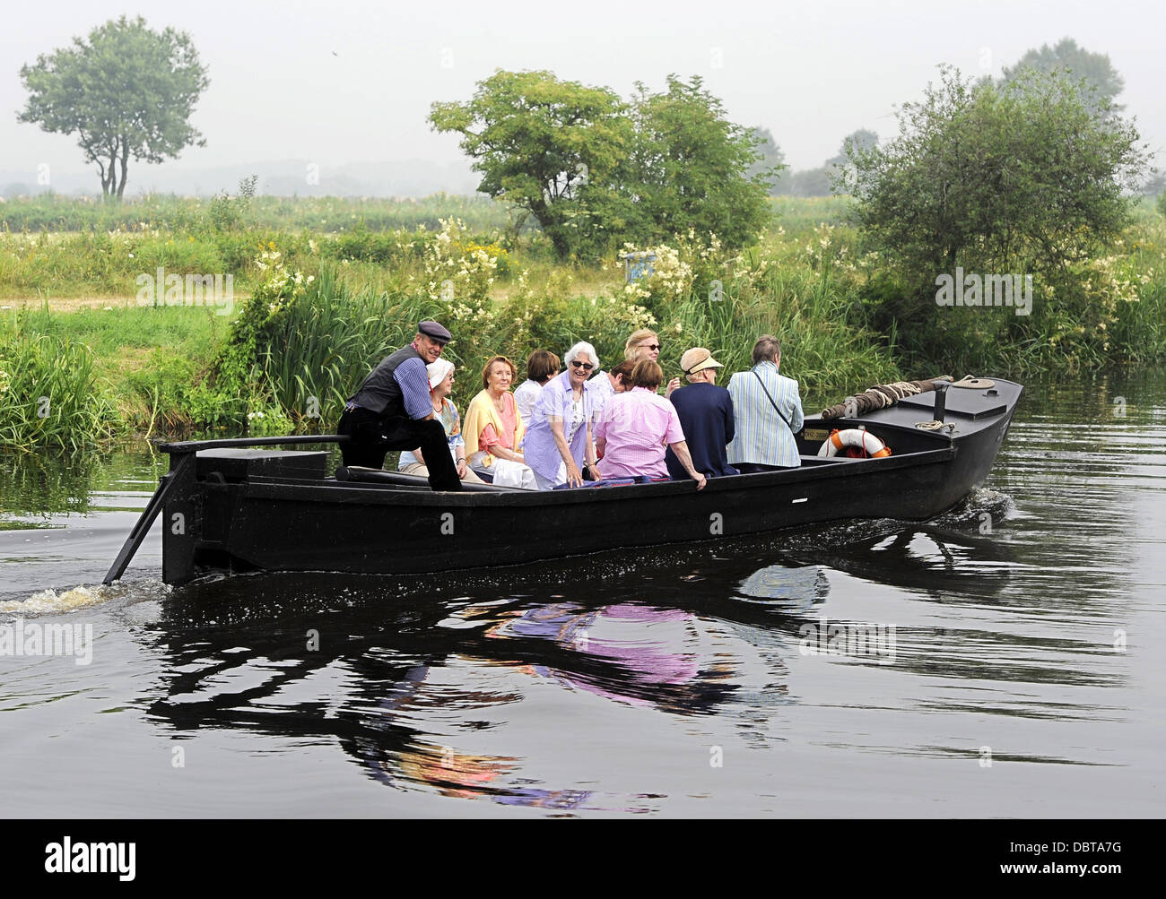 Les touristes s'asseoir dans un récipient sur le gazon Hamme rivière à travers le Teufelsmoor moorland de Osterholz-Scharmbeck à Neu Helgoland près de Worpswede, Allemagne, 25 juillet 2013. À partir de la tourbe le Teufelsmoor moorland utilisé pour être transportés par ces bateaux black oak à l'orifice de la tourbe à Brême. Photo : Ingo Wagner Banque D'Images