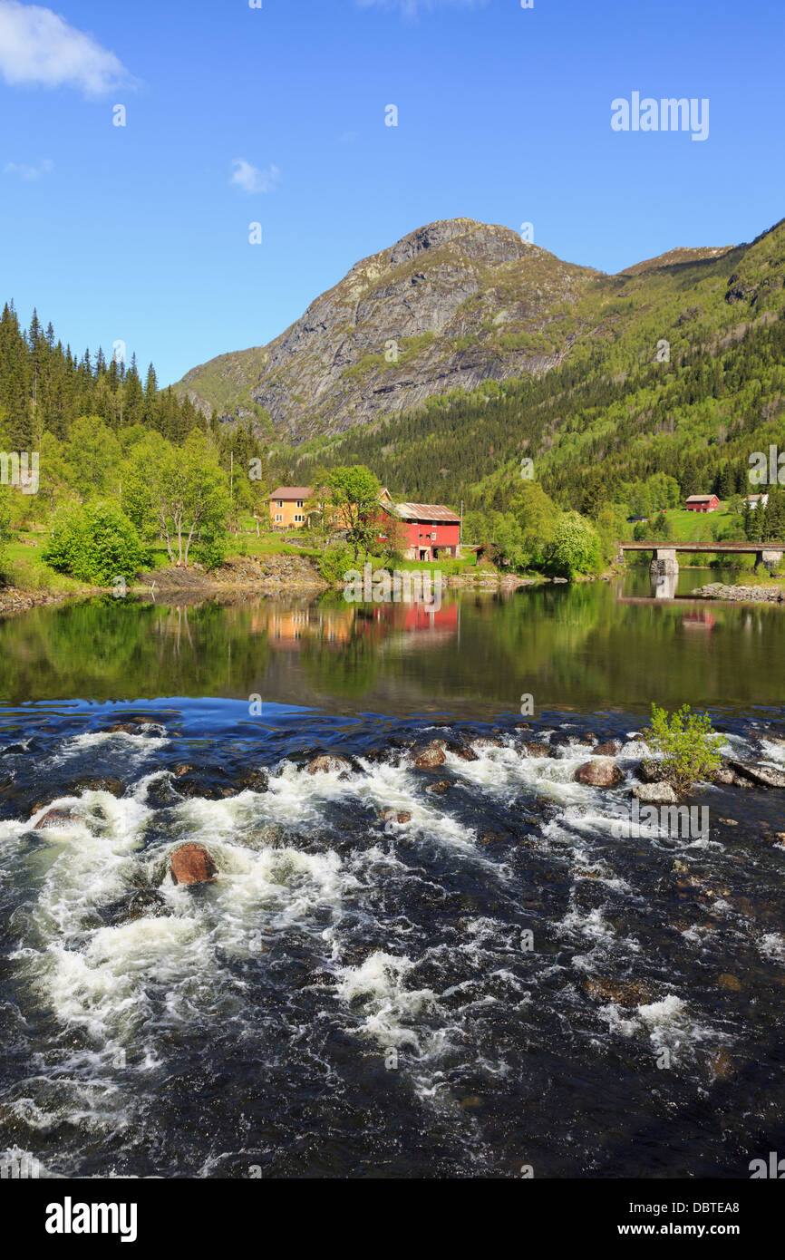 Vue sur l'eau qui coule au norvégien typique maison de ferme et grange rouge reflète dans Smorkleppai River. La Norvège Telemark Grungedal Banque D'Images