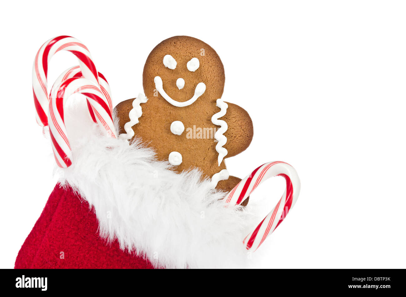 Gingerbread Man cookie et des cannes de bonbon dans le sac-cadeau de Noël rouge sur fond blanc Banque D'Images