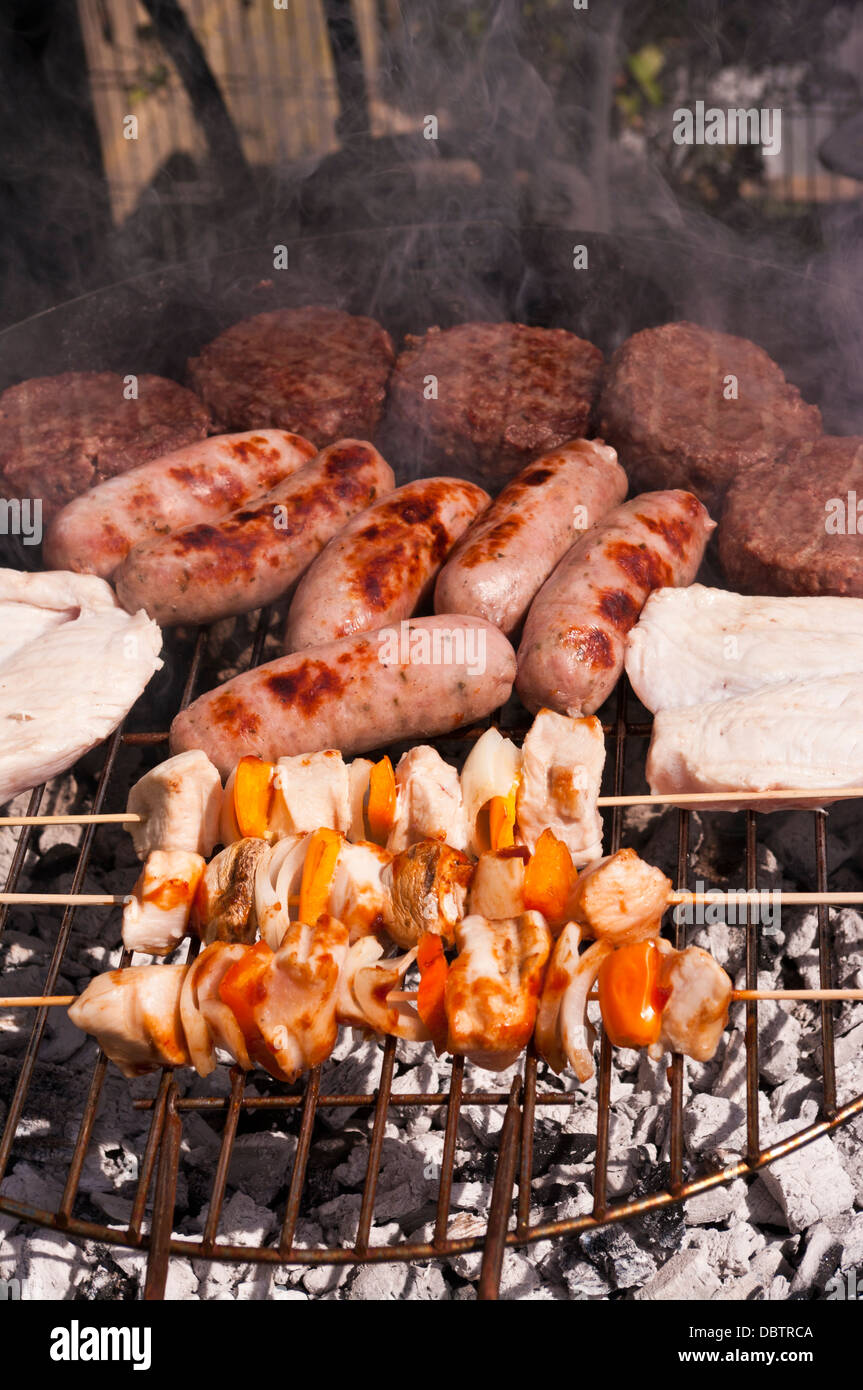 L'alimentation des hamburgers de poulet brochettes de saucisses Beefburgers et cuisson sur un Bar B Q Banque D'Images