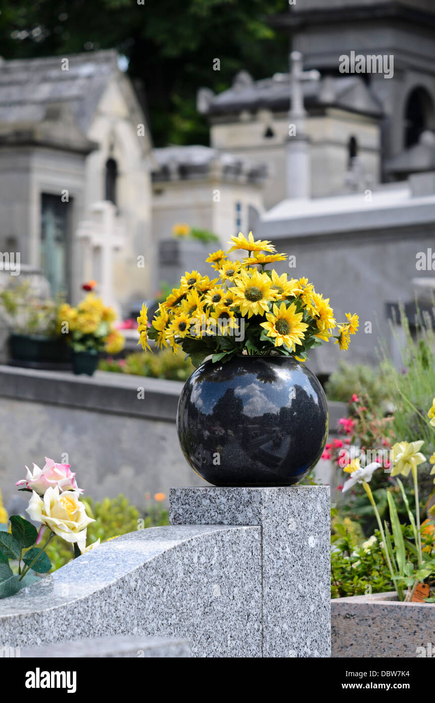 Des fleurs en plastique sur une pierre tombale Banque D'Images