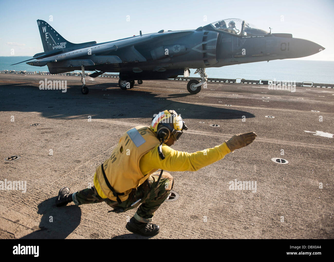 L'Aviation de l'US Navy un maître de Manœuvre signale le pilote d'un Harrier AV-8B fighter jet qu'il est autorisé à lancer depuis la cabine de pilotage du navire d'assaut amphibie USS Bonhomme Richard le 4 août 2013 dans la mer d'Oman. Banque D'Images