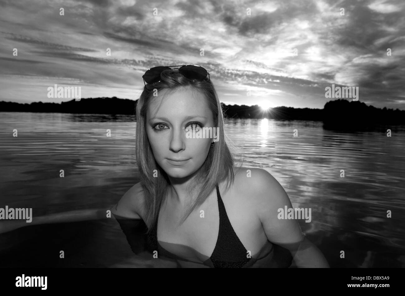 Fille dans le lac avec soleil derrière Banque D'Images
