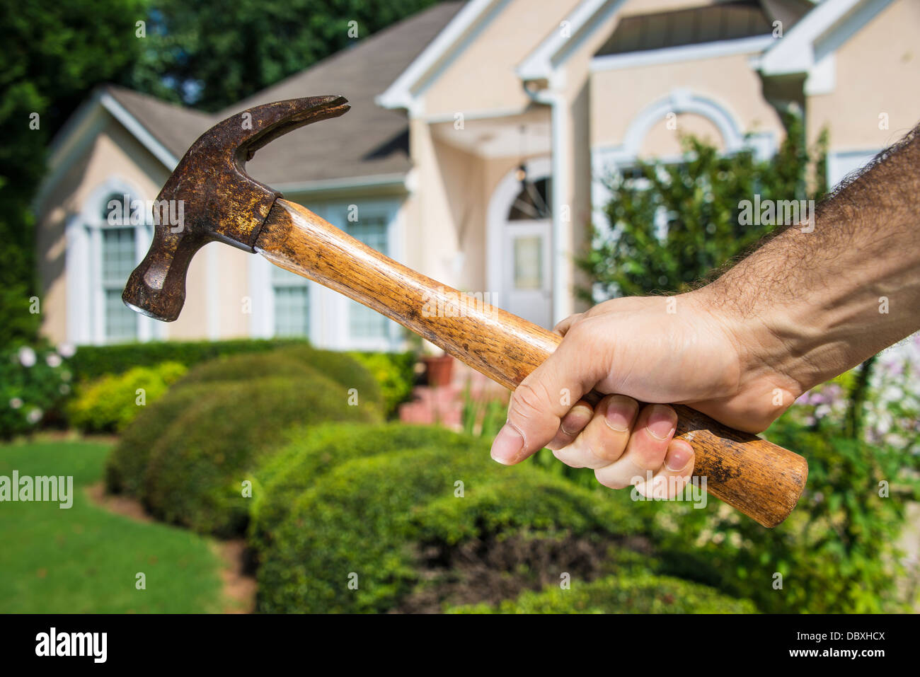 Man's hand holding hammer en face d'une maison d'accueil indiquant l'amélioration et à l'entretien. Banque D'Images