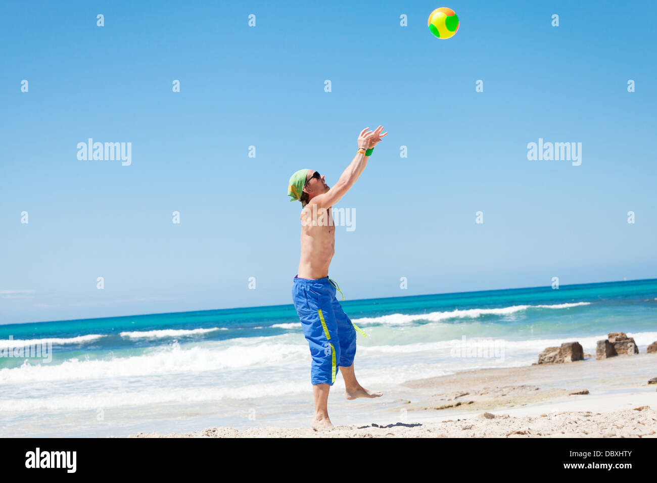 Beau jeune homme jouer au volley sur la plage l'été Banque D'Images