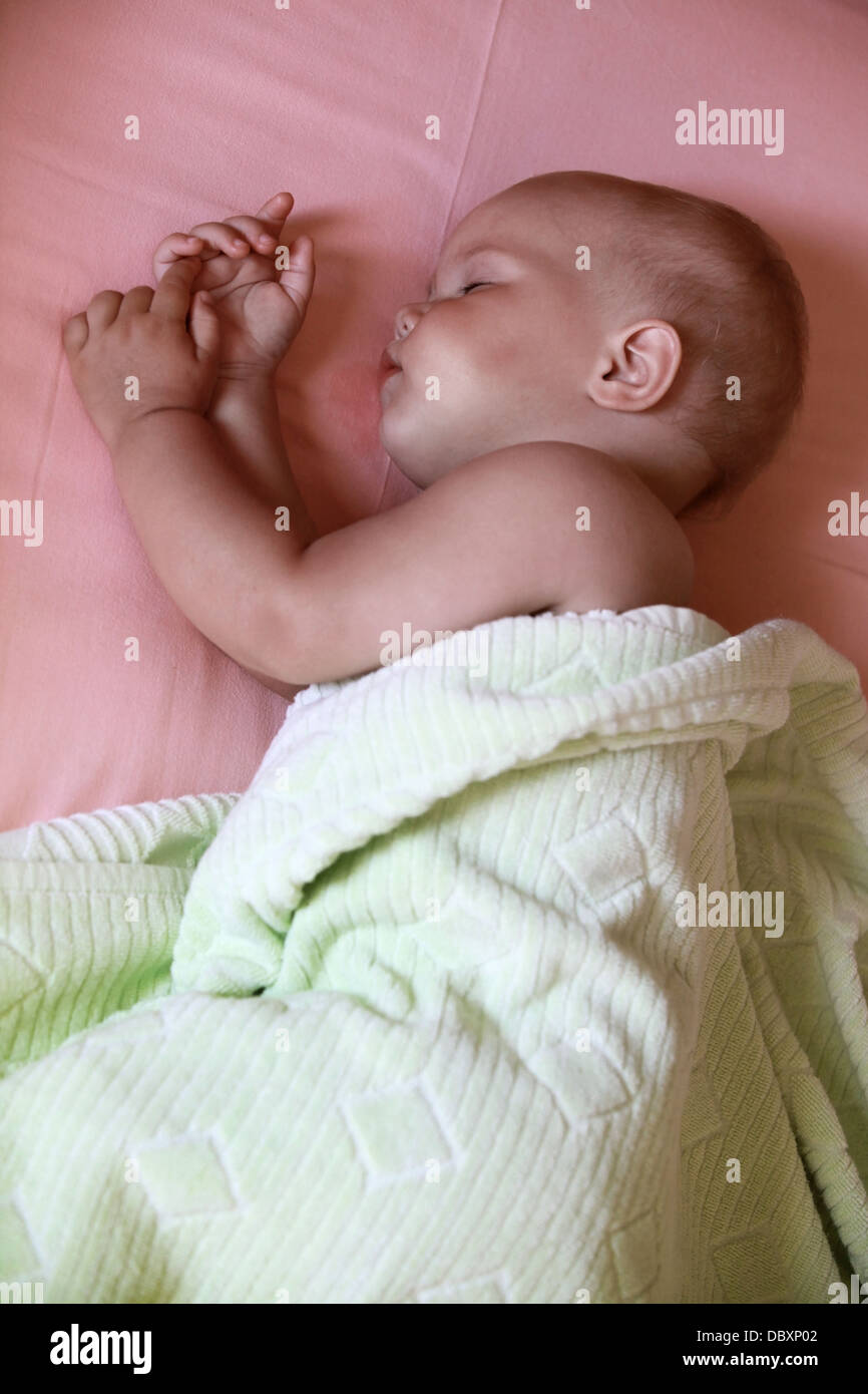 Petit bébé dort dans le lit sous une couverture souple Banque D'Images