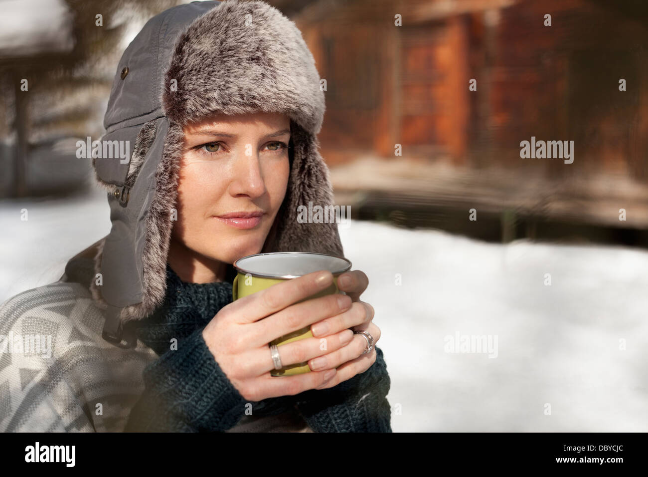 Pensive woman in fur hat de boire du café à l'extérieur de cabine Banque D'Images