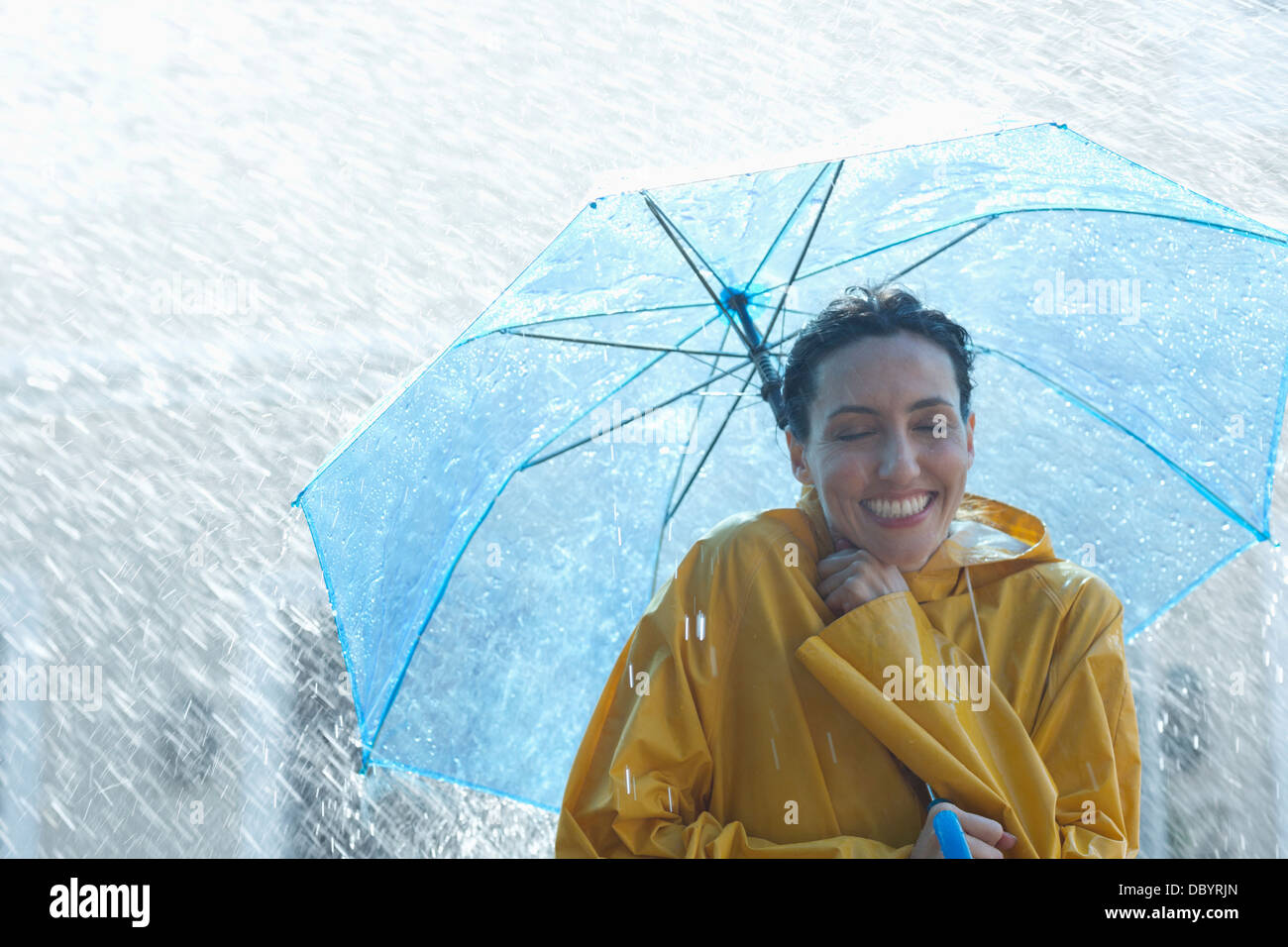 Happy woman under umbrella in rain Banque D'Images