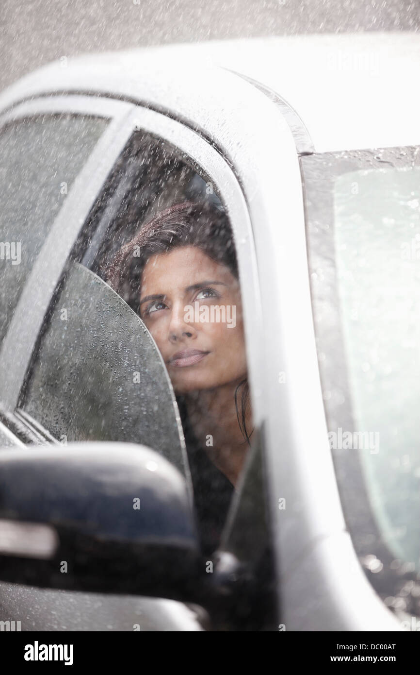 Businesswoman in car looking up at rain Banque D'Images