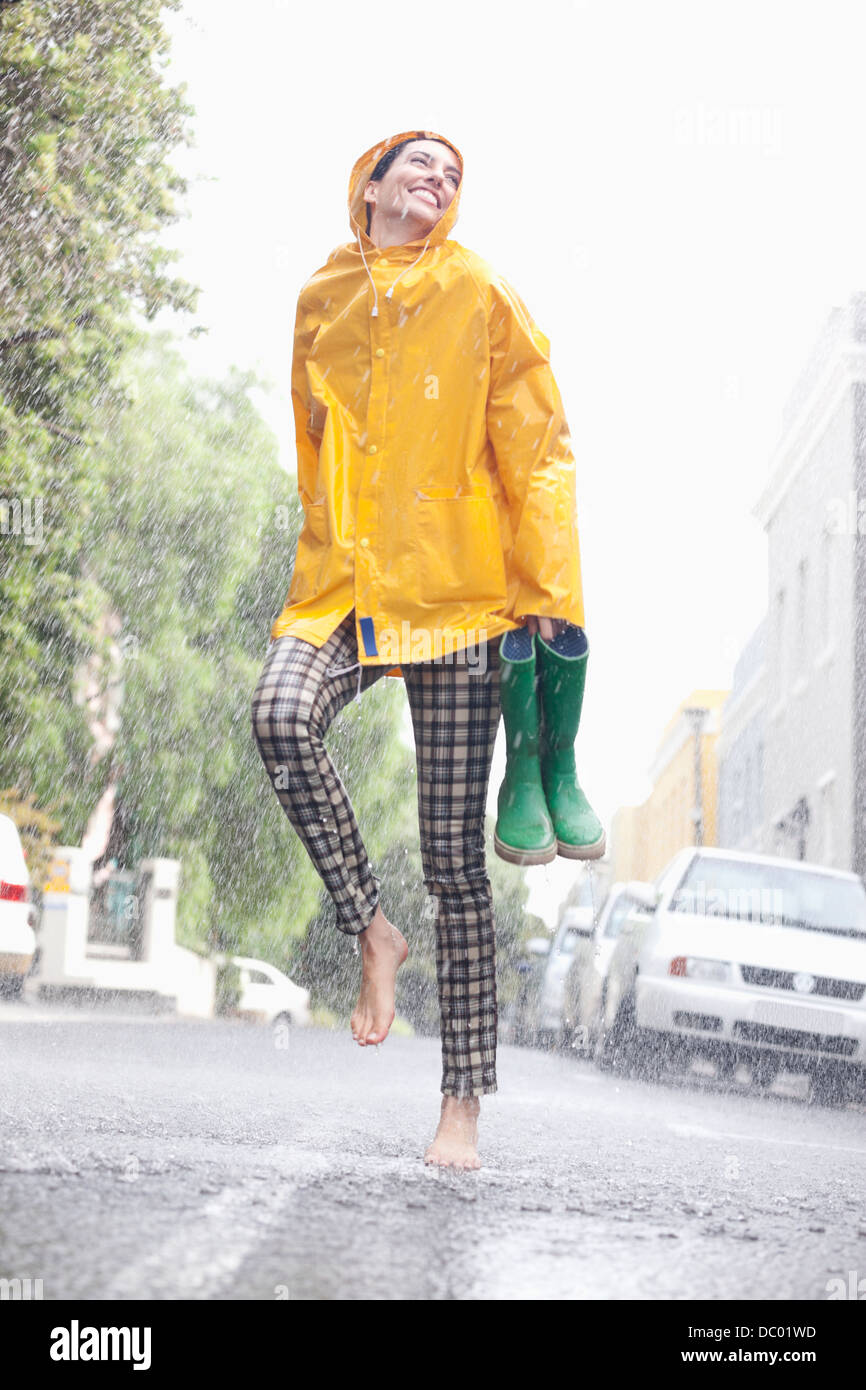 Happy woman dancing barefoot in rainy street Banque D'Images