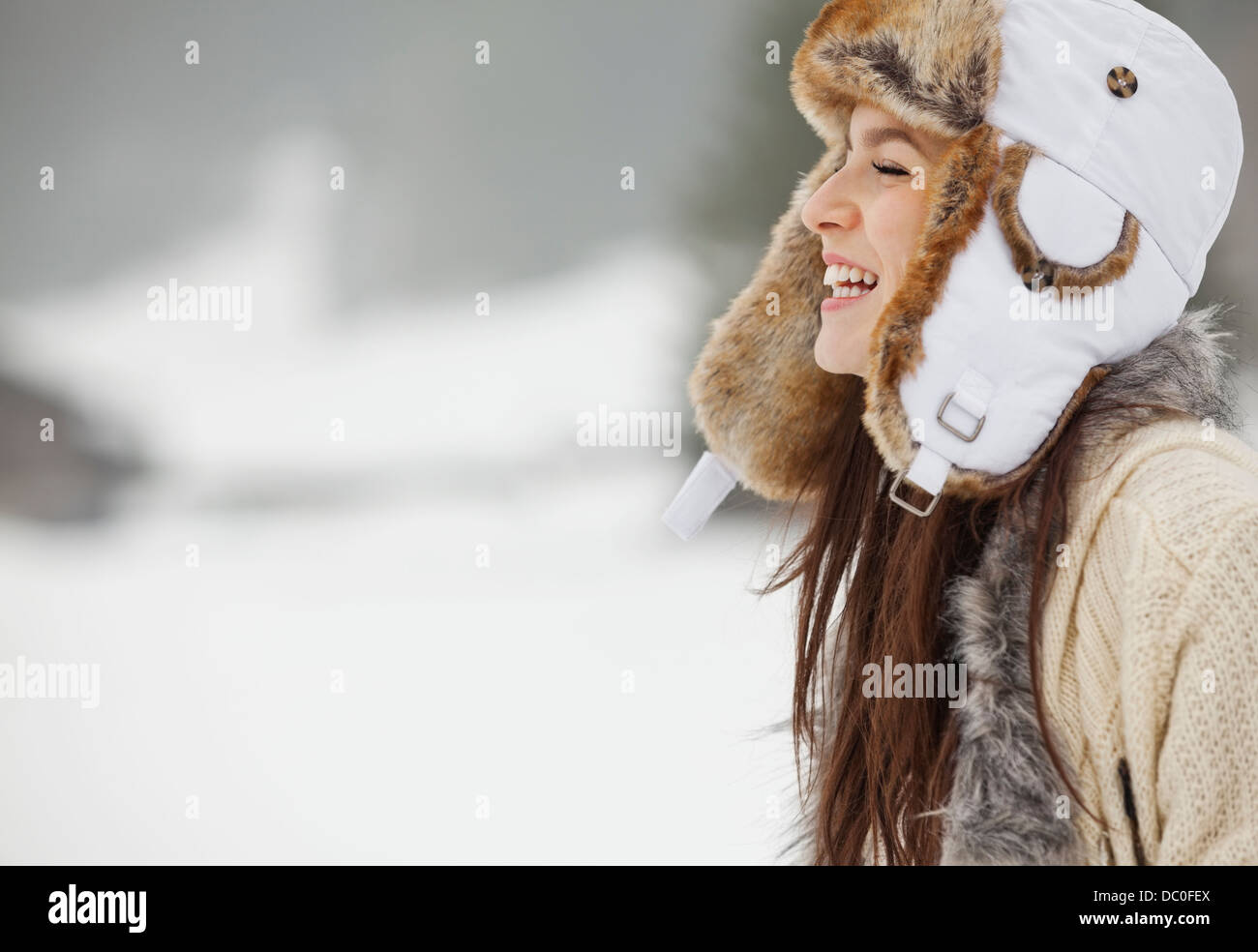 Happy woman wearing fur hat in snow Banque D'Images