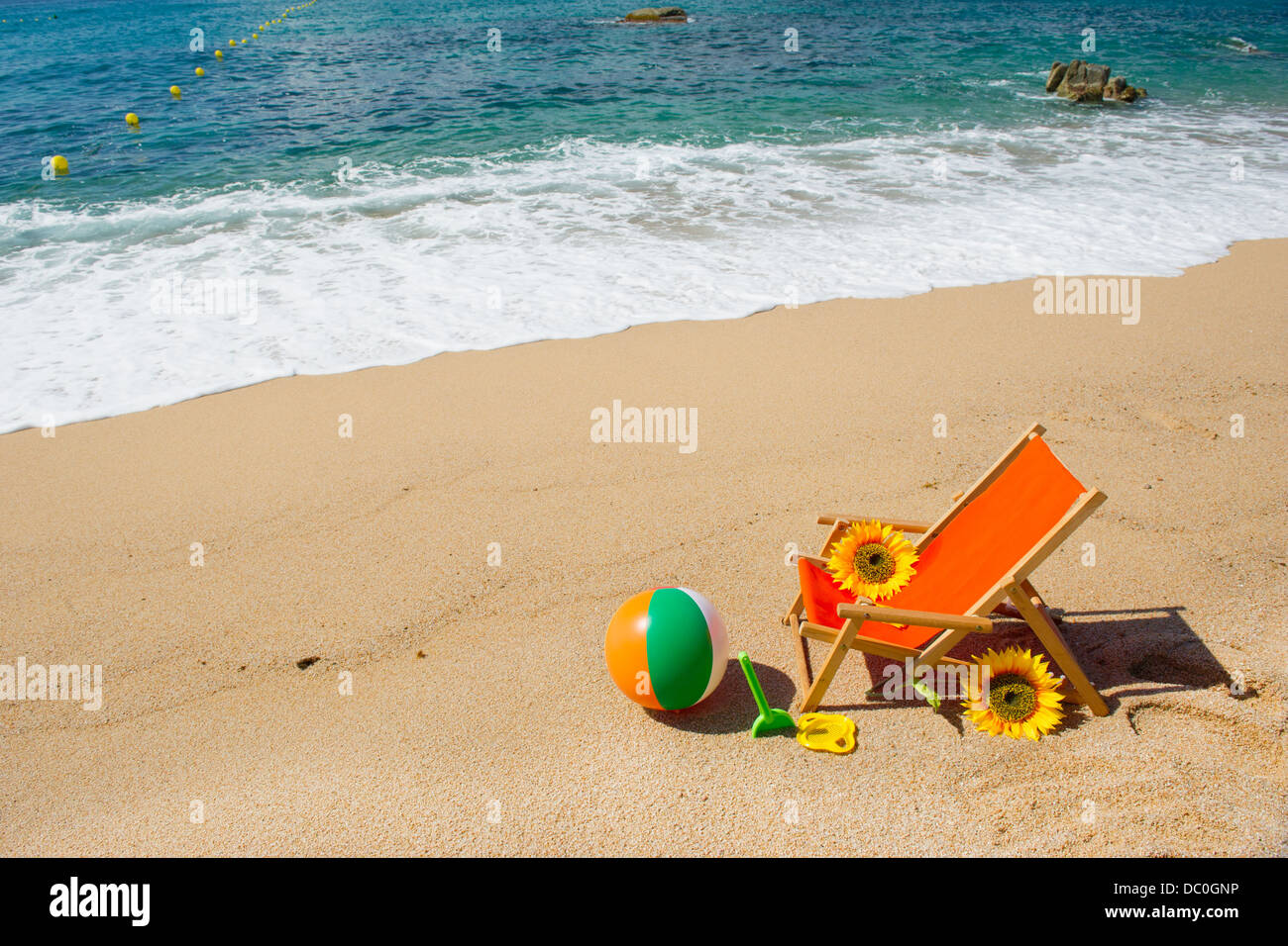 Chaise de plage vide avec des fleurs et des jouets à la mer Banque D'Images