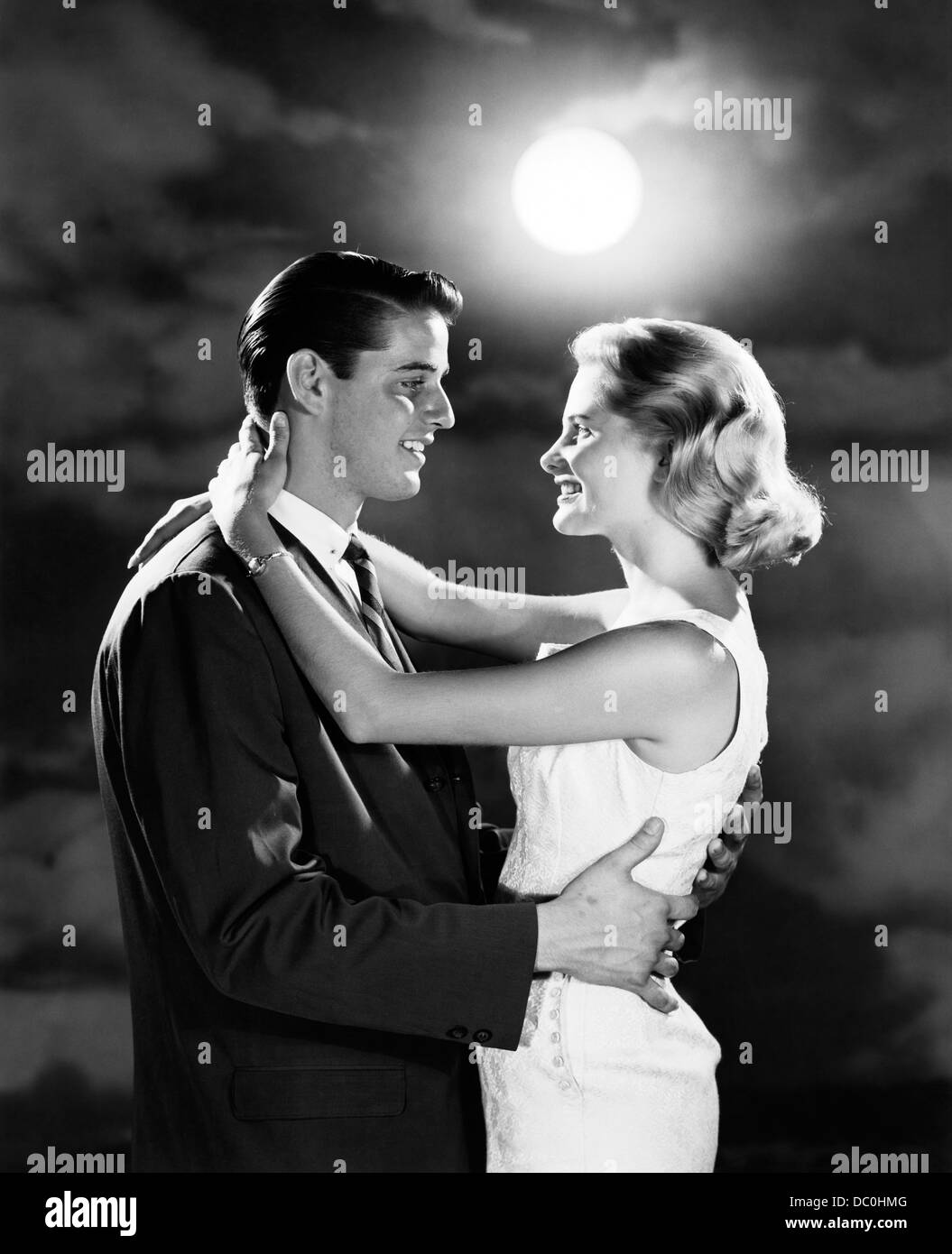 1960 YOUNG COUPLE EMBRACING IN MOONLIGHT Banque D'Images