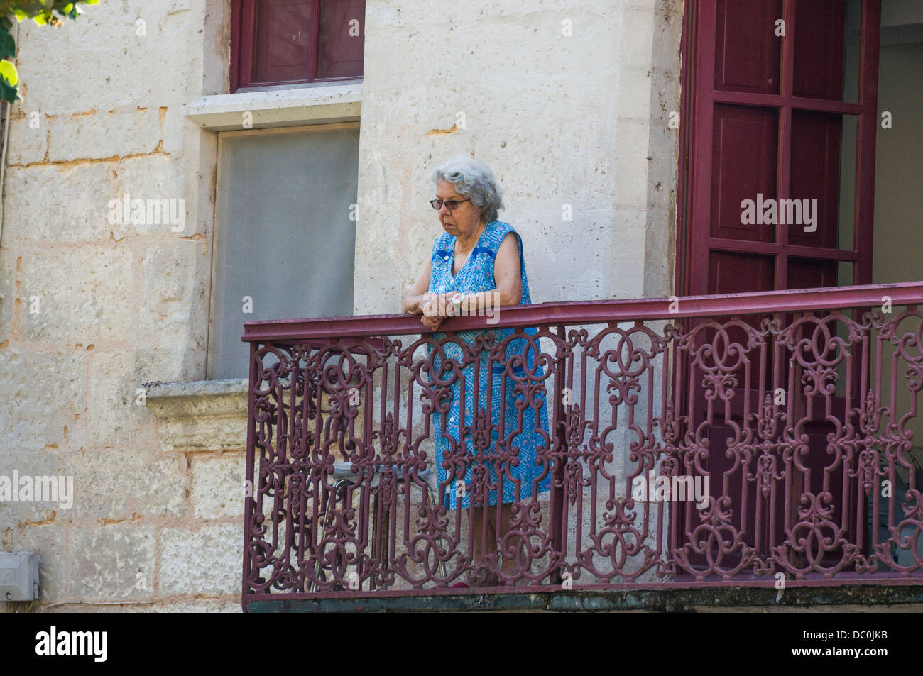 Une vieille dame à lunettes français debout, regardant de son balcon, sur la commune de Brantôme, en Dordogne dans le sud-ouest de la France, l'Europe. Banque D'Images