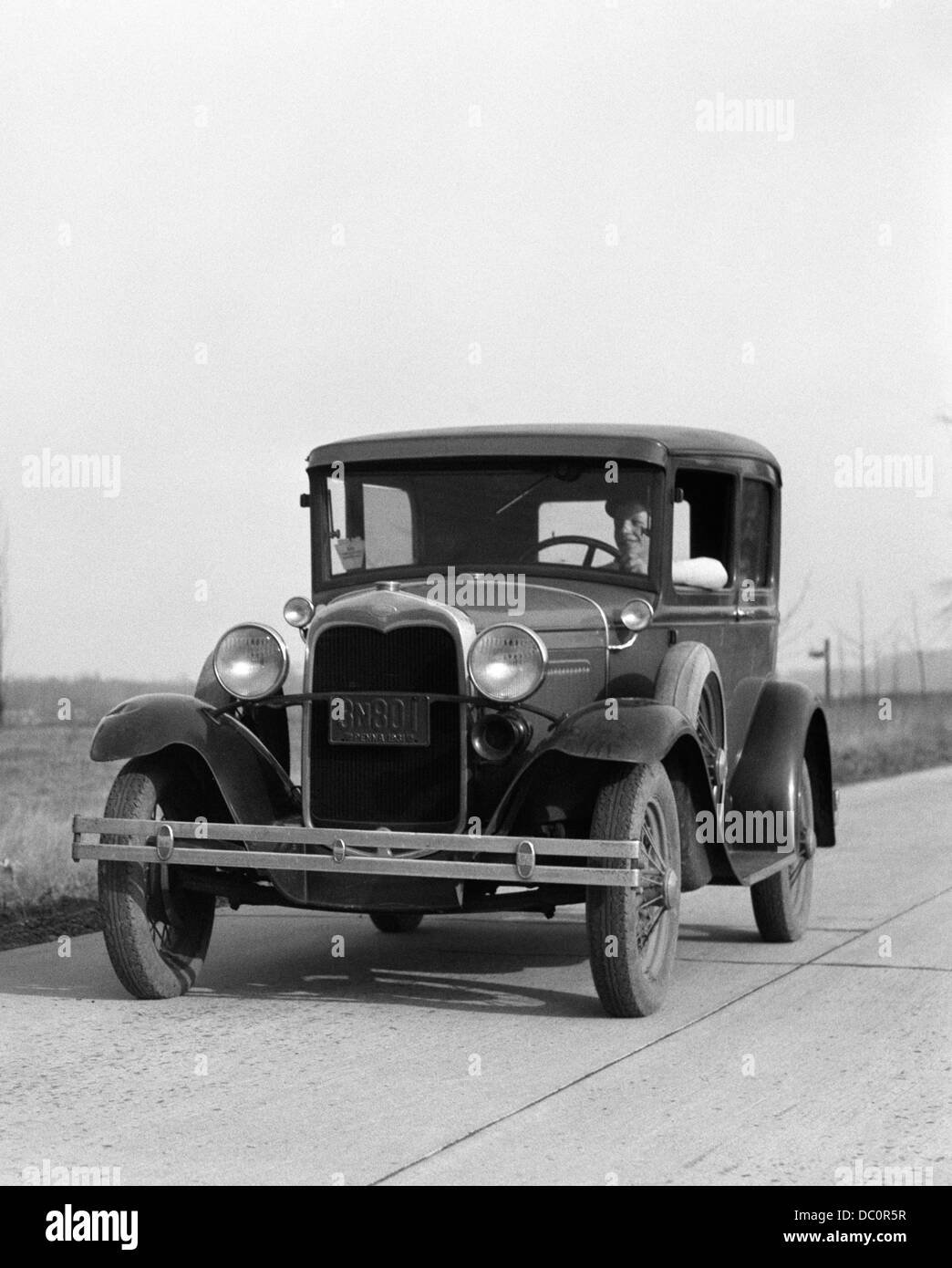 1930 JEUNE HOMME conduisant une voiture Ford modèle OUTDOOR Banque D'Images